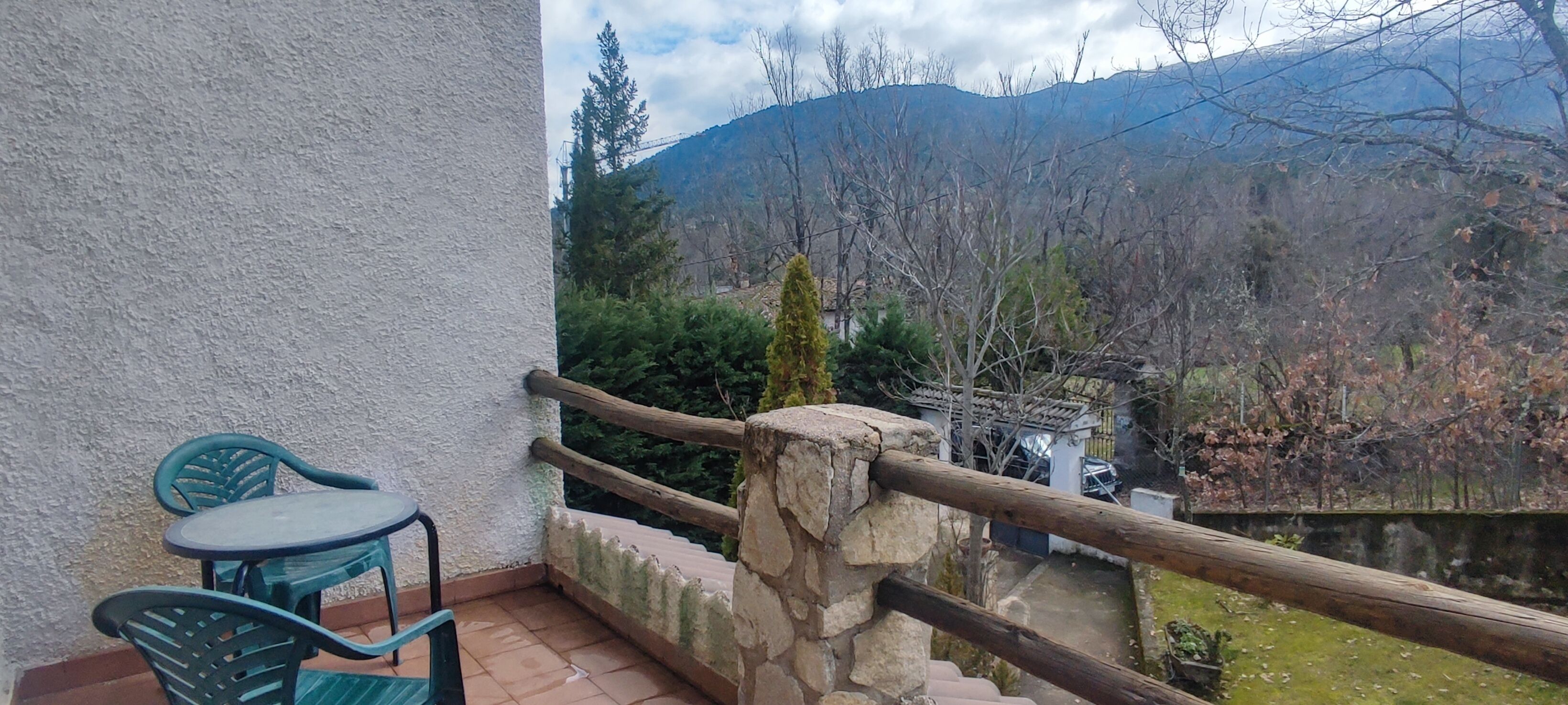 Un balcon avec une balustrade en pierre, une table et des chaises.