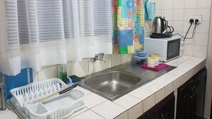 Una cocina con un lavabo, un microondas y una tetera sobre la encimera.