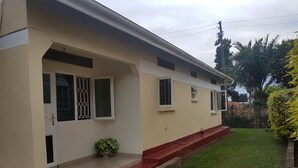 Una casa de dos pisos con un escalón delantero rojo, un pequeño porche y un césped verde.