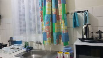 Una cocina con un lavamanos, un hervidor y un microondas.