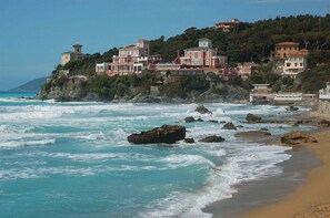 A coastal hotel with multiple buildings, a lighthouse, and rocky shoreline.