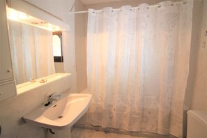 Un bagno con lavandino bianco, specchio e tenda da doccia.
