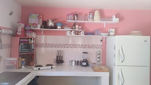 A kitchen with pink walls, white cabinets, and various kitchen appliances including a microwave, stove, and refrigerator.