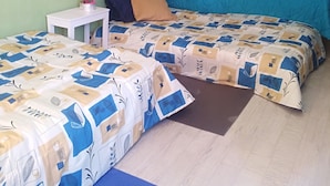 A bedroom with two beds, a small table, and a mirror.