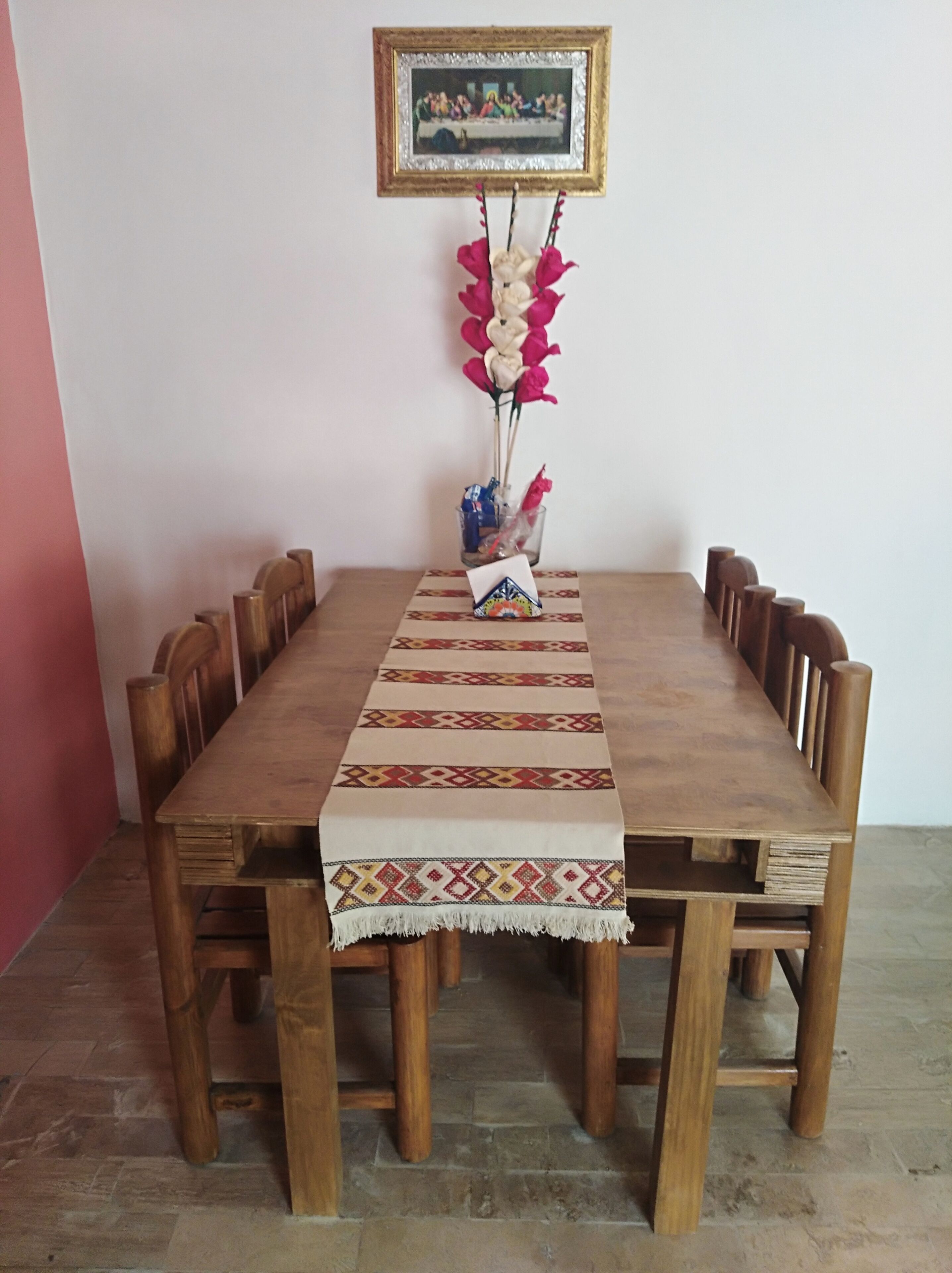 A wooden dining table with a patterned runner, surrounded by wooden chairs.