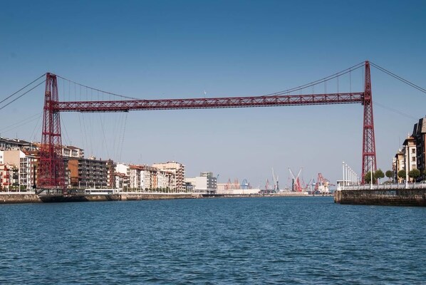 A red bridge spanning a body of water with buildings on either side. - holiday home in galdames (galdames,vizcaya)