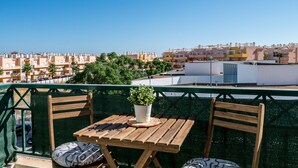 Eine Dachterrasse mit Holztisch und -stühlen, einem Blumentopf und Blick auf eine Wohngegend.