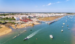 Vue aérienne d’une ville côtière avec un port de plaisance, des bateaux et des bâtiments le long de la côte.
