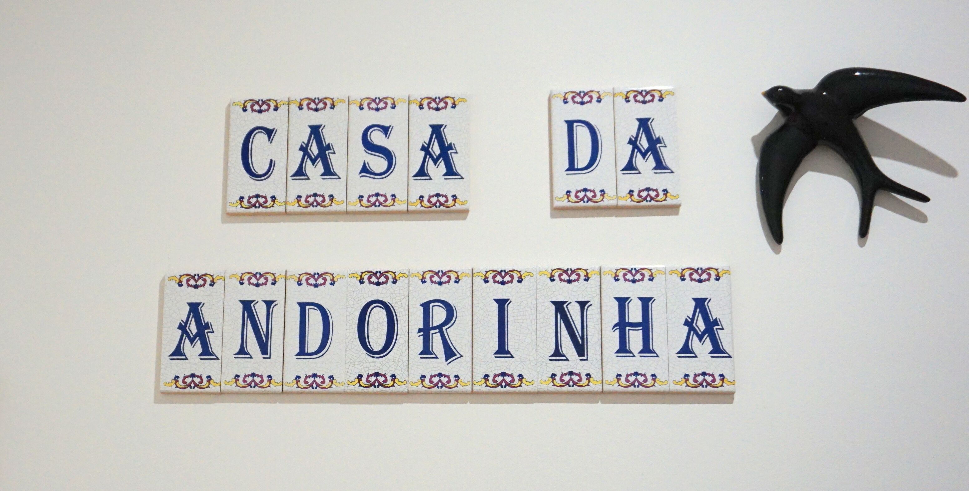 A wall with tiles spelling out 'CASA DA ANDORINHA' and a black bird figurine.