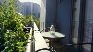 Un balcó amb plantes en testos, una taula i un fanal blanc.