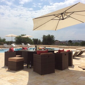 A poolside area with wicker furniture and umbrellas, a pool, and a view of the city. - Villa Marietta - Idyllic Country Villa With Large Private Pool (Cisternino)