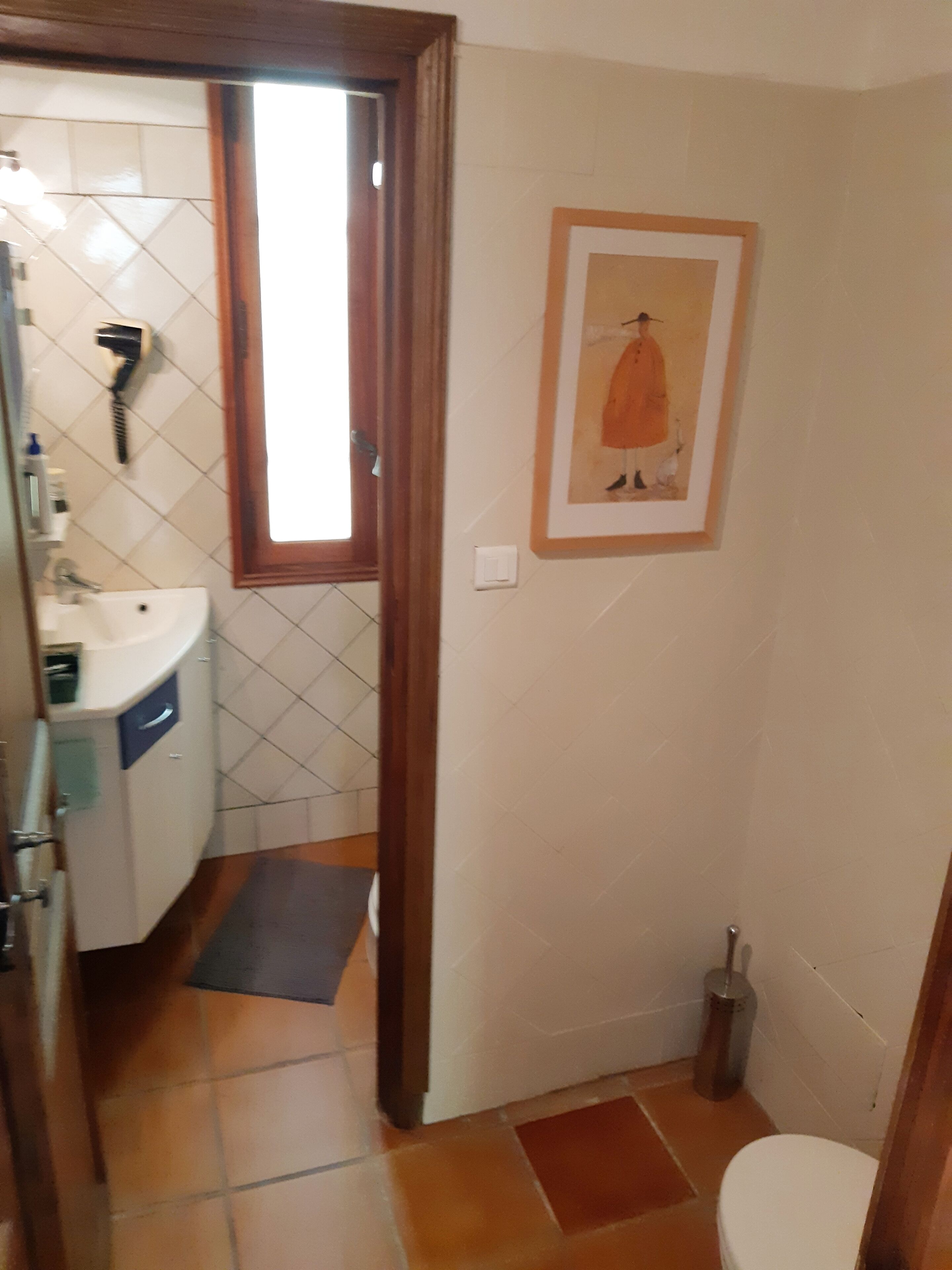 A bathroom with a sink, toilet, and a framed picture on the wall.