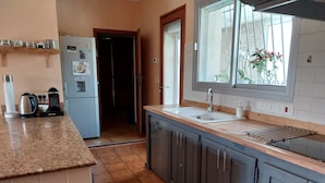 Una cocina con encimera de granito, pileta integrada y ventana con vista a plantas.