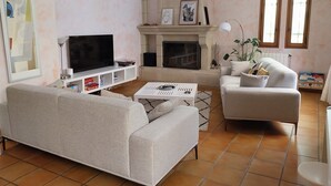 Una sala de estar con sofá, mesa de centro, televisión, chimenea y estantería.