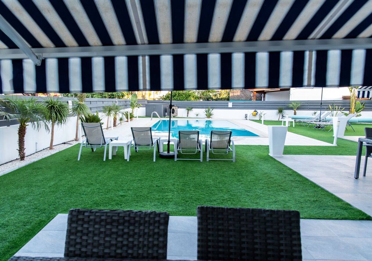 A covered outdoor area with a pool, artificial grass, and seating.