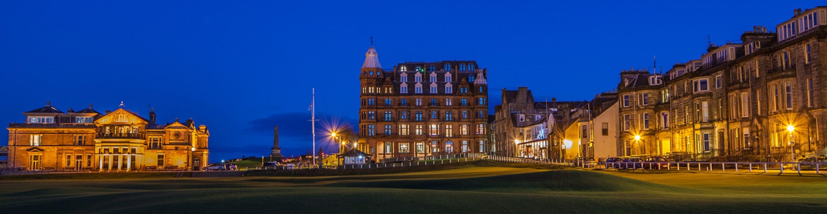 Un bâtiment historique à l’architecture classique, une pelouse bien entretenue et un ciel nocturne dégagé.