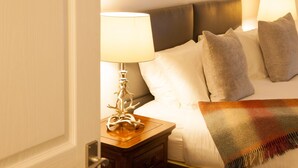 Een hotelkamer met een bed, een nachtkastje met een lamp en een dekbed.