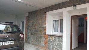 Cot estacionat en un garatge amb paret de pedra i una porta que dona a una habitació.