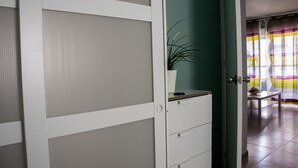 A room with a sliding door, a potted plant, a small table, and a striped curtain. - LOS NARANJOS APARTMENT.  (Matalascañas)