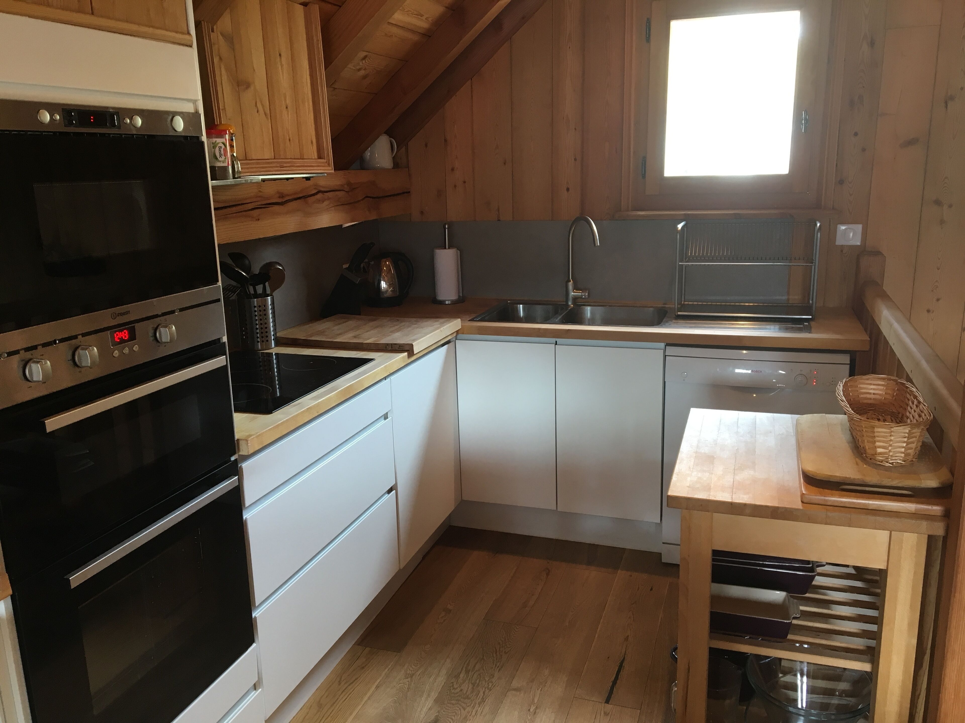 Una cocina con gabinetes de madera, un horno negro, un lavamanos y una ventana.