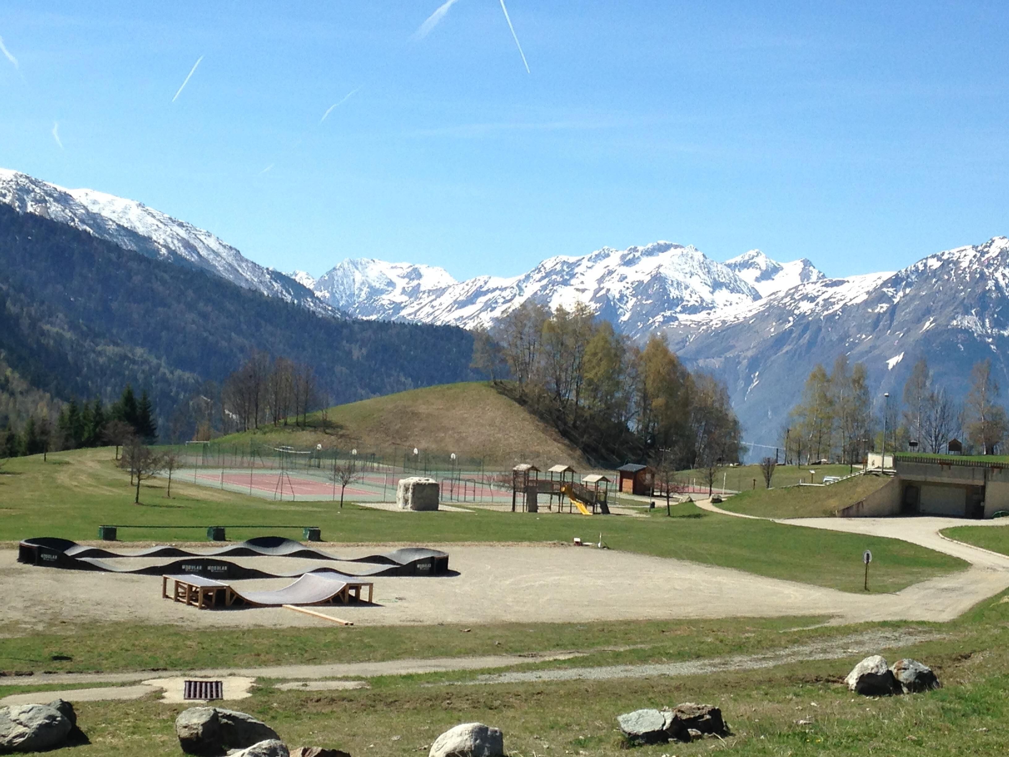 A park with a playground, a dirt path, and a small building.