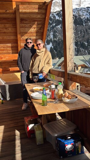 A wooden deck with a table set for two, a bottle of beer, and a bottle of water.
