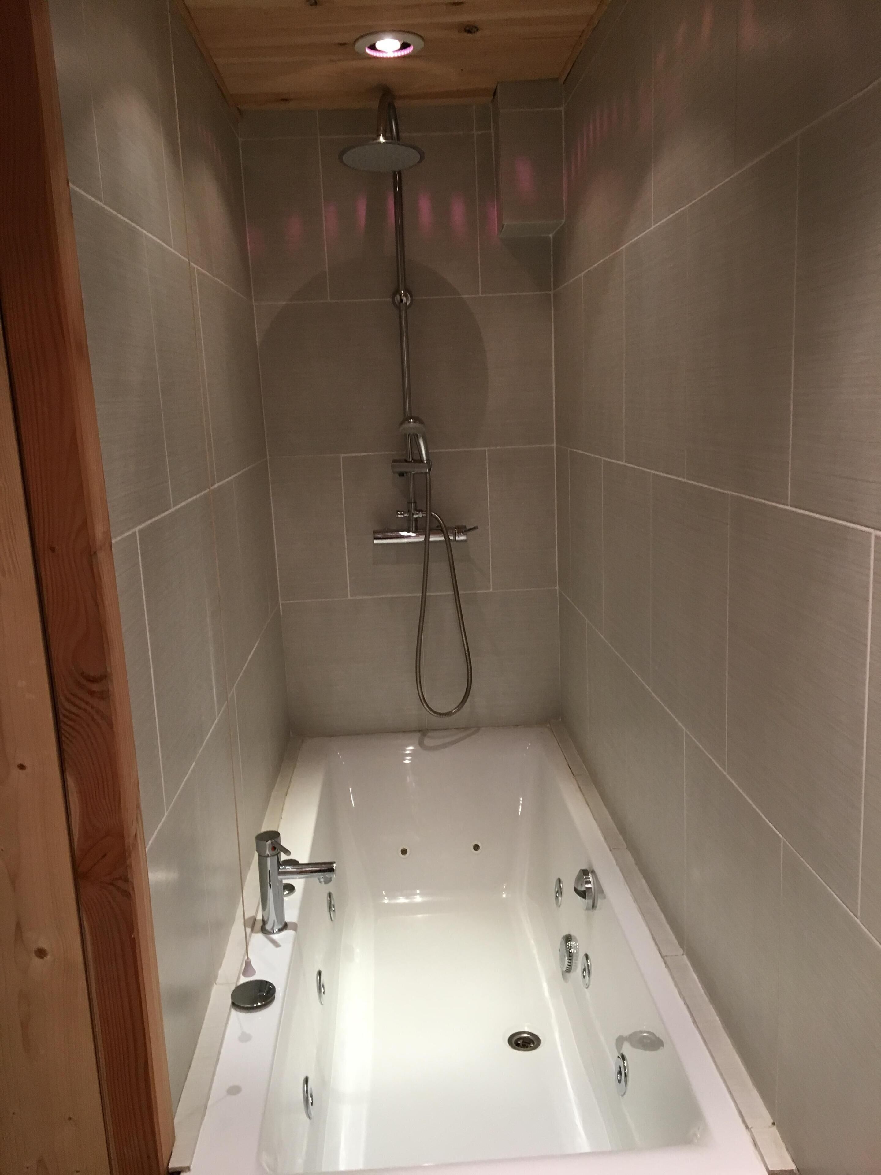Un baño moderno con una bañera independiente, un cabezal de ducha manual y un grifo empotrado.