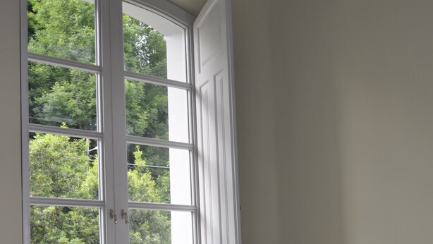 Ein Schlafzimmer mit großem Fenster, einem Bett, einem Nachttisch und einem Beistelltisch.