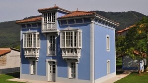 Ein zweistöckiges Gebäude mit blauer Fassade, weißem Zierrat und einem roten Ziegeldach.