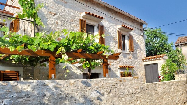A stone building with wooden shutters, a pergola with vines, and a stone wall. - Stone house with charm (Medulin)