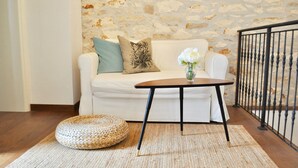 A white sofa with a woven ottoman and a small table in front, against a stone wall. - Stone house with charm (Medulin)