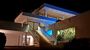 Une maison moderne à plusieurs étages, dotée d’un escalier en verre, d’un balcon et d’un mur végétal.