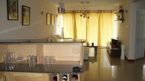 Une cuisine dotée d’un plan de travail en bois, d’un espace de rangement pour les bouteilles de vin et d’un coin repas avec une table et des chaises.