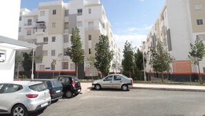 A parking lot with several cars, including a white Renault and a silver sedan, in front of a row of white apartment buildings with balconies. - apartment 6 person 10 minutes from the beach (agadir)