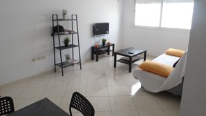 A modern living room with a sofa, a coffee table, a TV, and a bookshelf. - apartment 6 person 10 minutes from the beach (agadir)