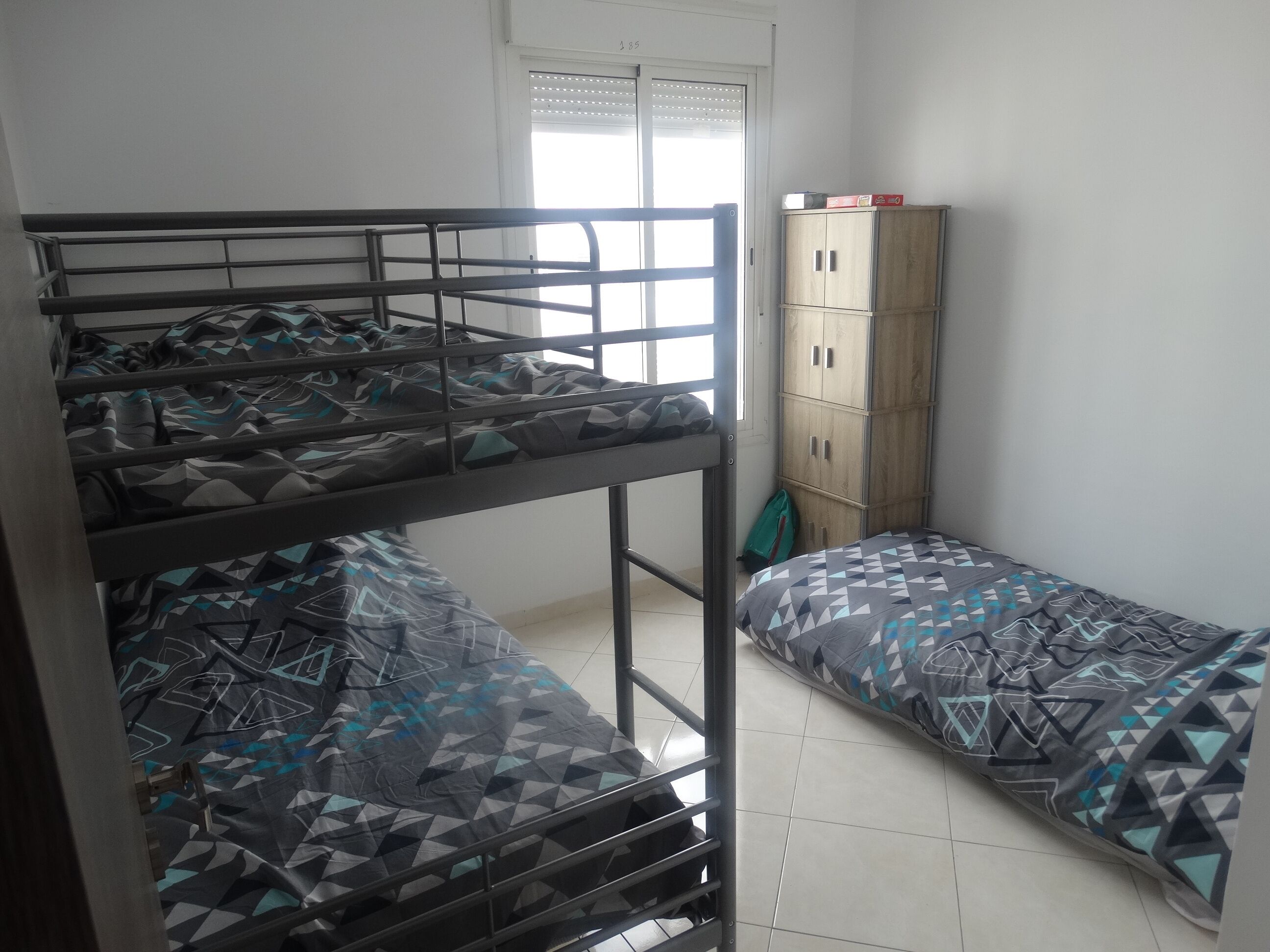 Un dormitorio con literas, un armario y una ventana con persianas.