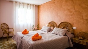 A hotel room with two beds, a wicker chair, a small table, and a window with curtains. - Chalet on the beach Valencia Mareny Sueca Cullera (Mareni de Barraquetes Sueca)