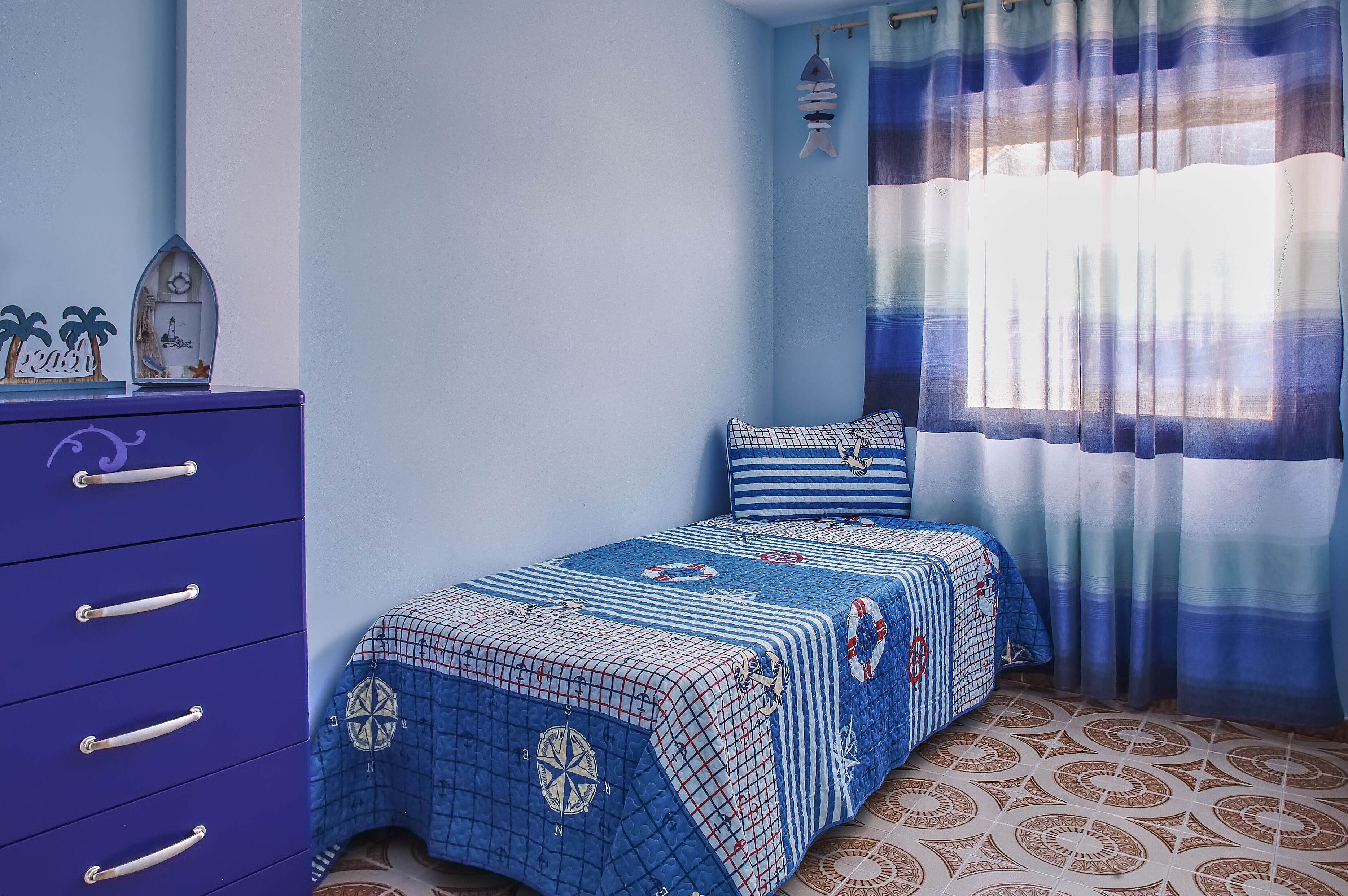 Un dormitorio con cama, cómoda y ventana con cortinas.