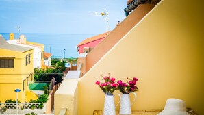 A balcony with a view of the sea, two white vases with pink flowers, and a white hat on a bamboo table. - Chalet on the beach Valencia Mareny Sueca Cullera (Mareni de Barraquetes Sueca)