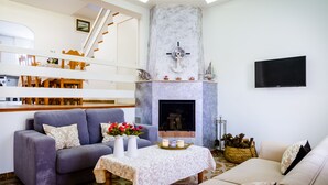 A living room with a fireplace, two sofas, a coffee table, and a TV mounted on the wall. - Chalet on the beach Valencia Mareny Sueca Cullera (Mareni de Barraquetes Sueca)