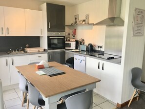 Kitchen features a central island with a sink, oven, and microwave, along with a refrigerator, toaster, and stainless steel range hood.