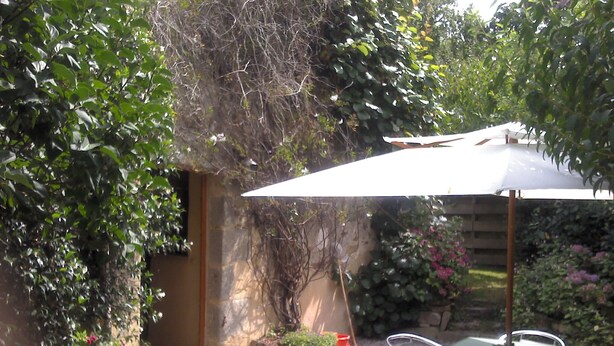 A patio area with a table and chairs, an umbrella, and a garden with various plants and flowers. - the barn of Paul, seasonal rental in the peninsula of Rhuys (Le Hézo)