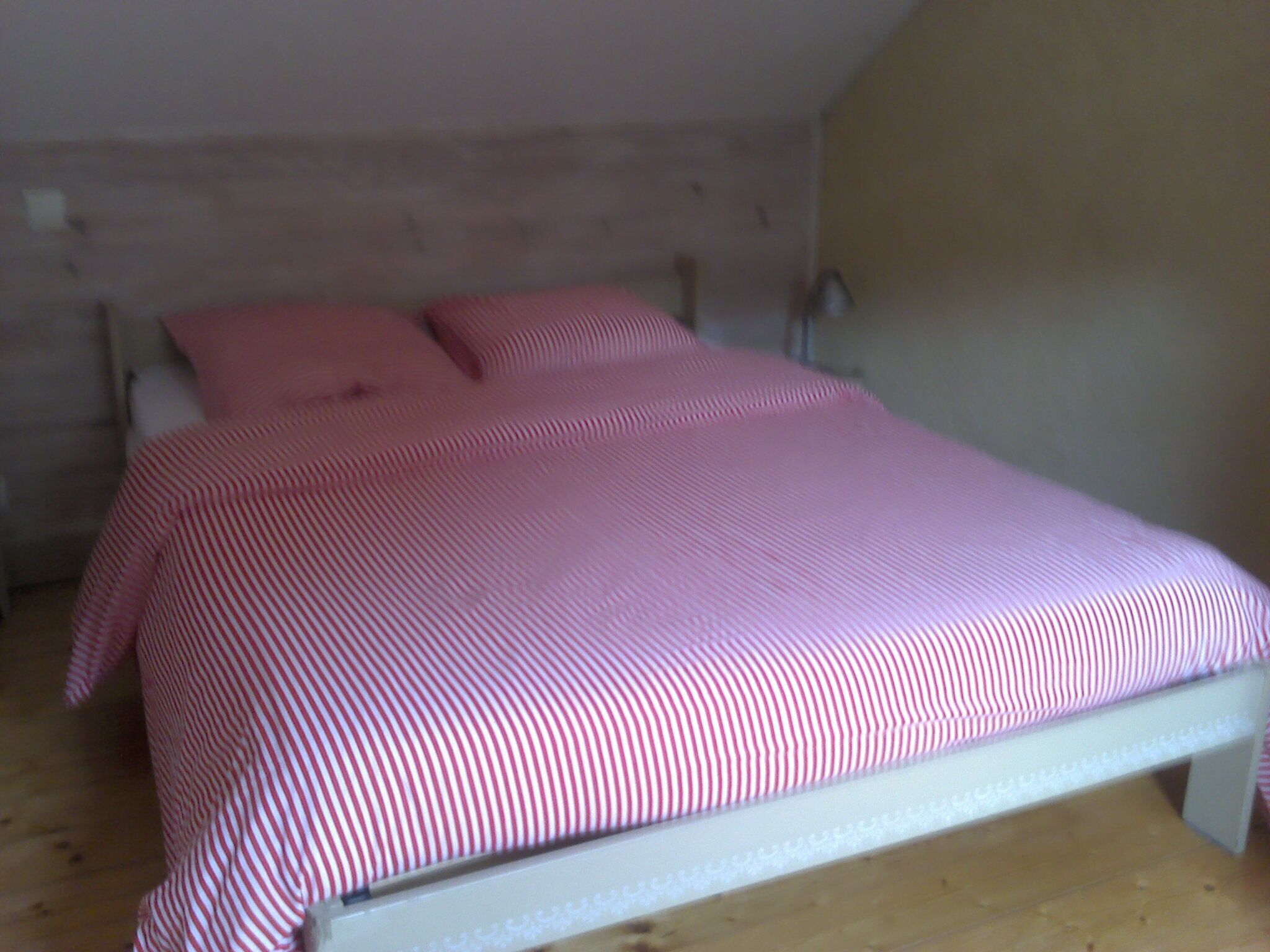 Un lit simple avec un cadre blanc et une couvre-lit à rayures rouges et blanches.