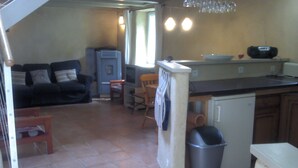 A compact living space with a kitchenette, a dining area, and a seating area with a sofa and chairs. - the barn of Paul, seasonal rental in the peninsula of Rhuys (Le Hézo)