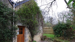 A rustic stone building with a wooden door, surrounded by greenery and a gravel path. - the barn of Paul, seasonal rental in the peninsula of Rhuys (Le Hézo)