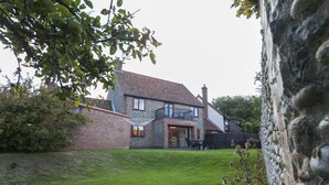 Une maison à deux étages avec une façade en briques, un balcon et une pelouse bien entretenue.