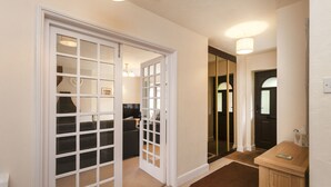Un couloir avec une porte blanche, une moquette marron et une petite table d’appoint en bois.
