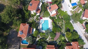 Vista aérea de una zona residencial con varias casas, cada una con piscina y tejados de tejas rojas.