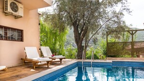 Una piscina con sillas de descanso y una pérgola.