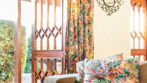 Una stanza accogliente con una porta in legno, tende floreali, un divano imbottito e un tappeto decorato.